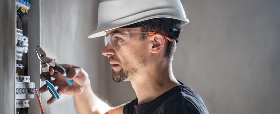 Man, an electrical technician working in a switchboard with fuses. Installation and connection of electrical equipment.